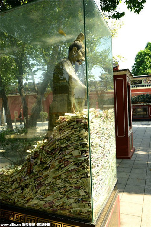 Bronze statues in Guangzhou scenic spot “swallowed” by banknotes and coins