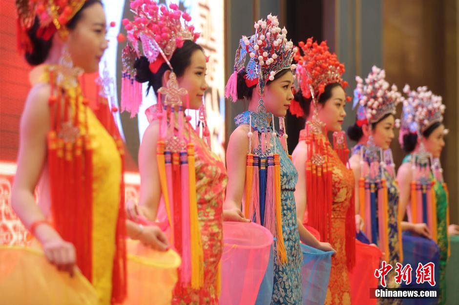 Models wearing phoenix coronet and cheongsam go down the runway
