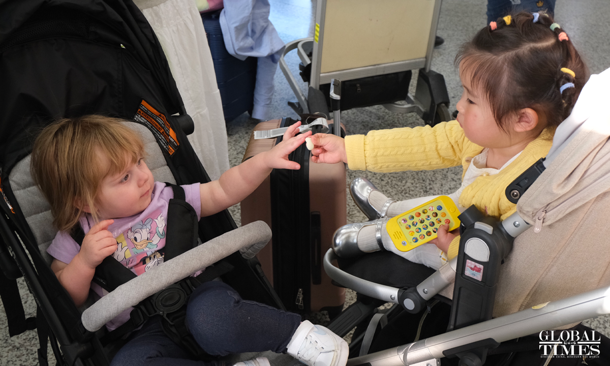 Rongrong's 19-month-old daughter (right) and Brecken's 16-month-old daughter share cookies at Shanghai Pudong Airport on March 22, 2025. Photo: Li Yawei/GT
